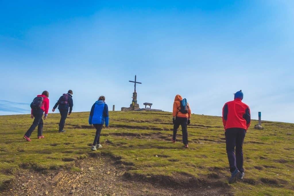 People hiking towards the cross on top of the Matagalls mountain