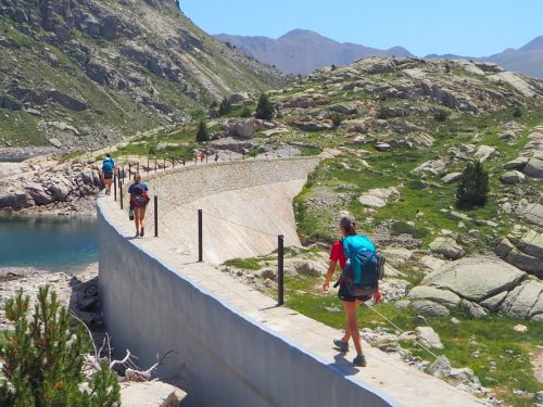 People walking the Carros de Foc trail next to the dam
