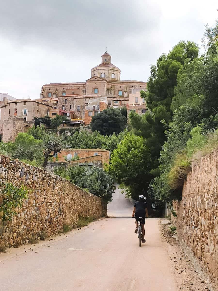 A person cycling towards the village of Mont-Roig del Camp in Tarragona